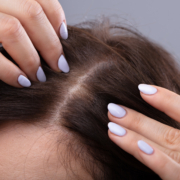 Woman looking at her scalp closely for hair growth. Laser light therapy can help stimulate and boost hair growth, especially when used alongside a prescription hair growth treatment.